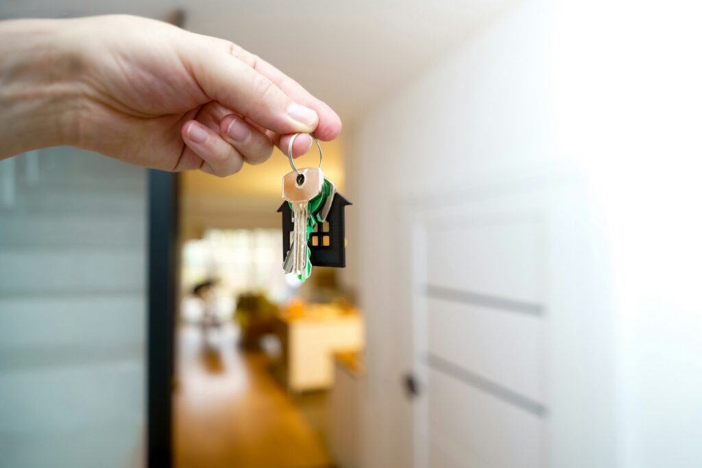 Hand holding house keys at the entrance to a home