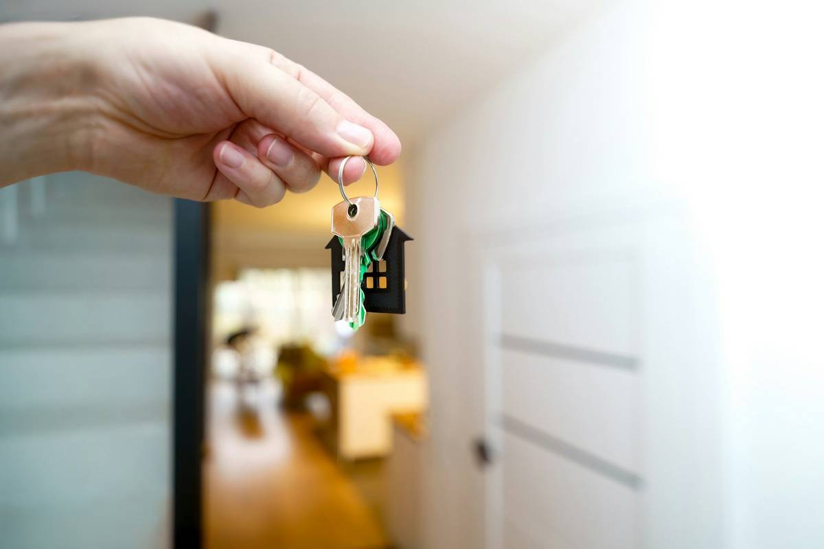 Hand holding house keys at the entrance to a home