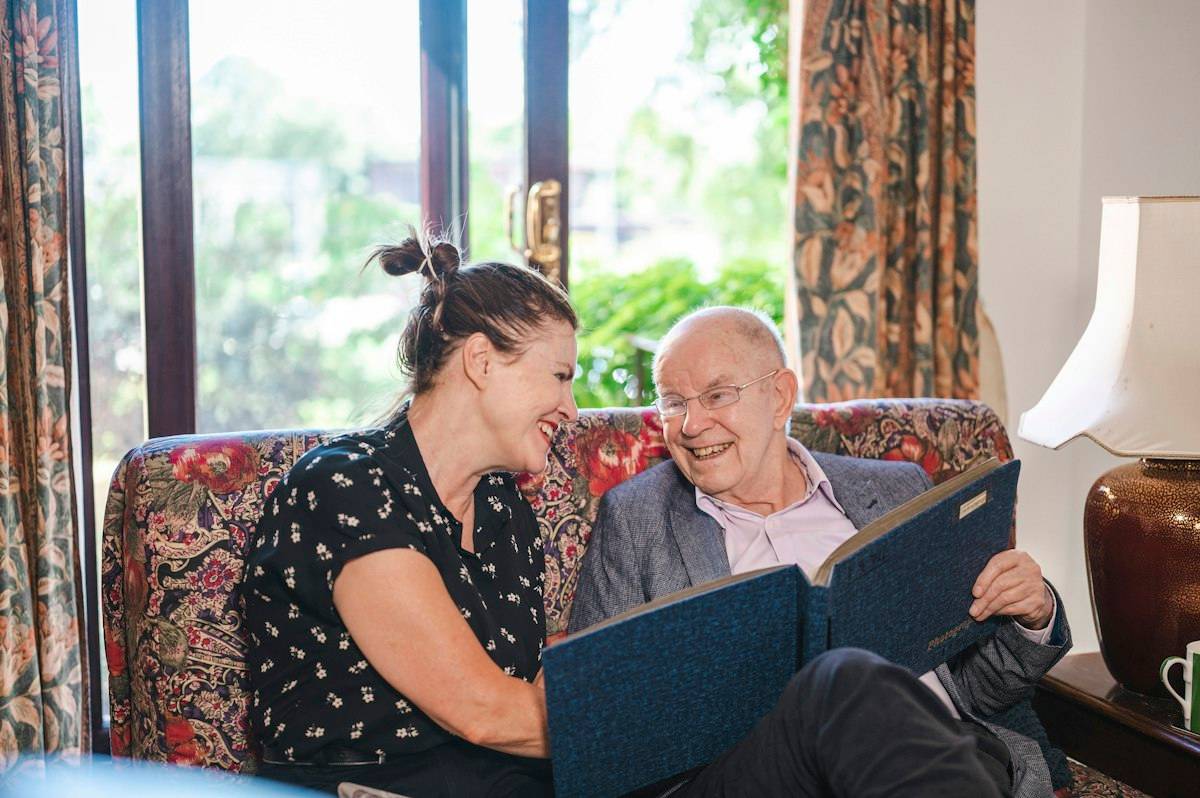 Woman reading with an older man in a care setting