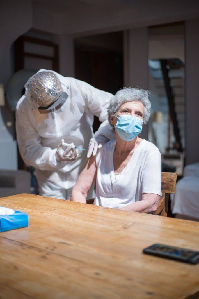 Healthcare professional giving a vaccine to an older woman