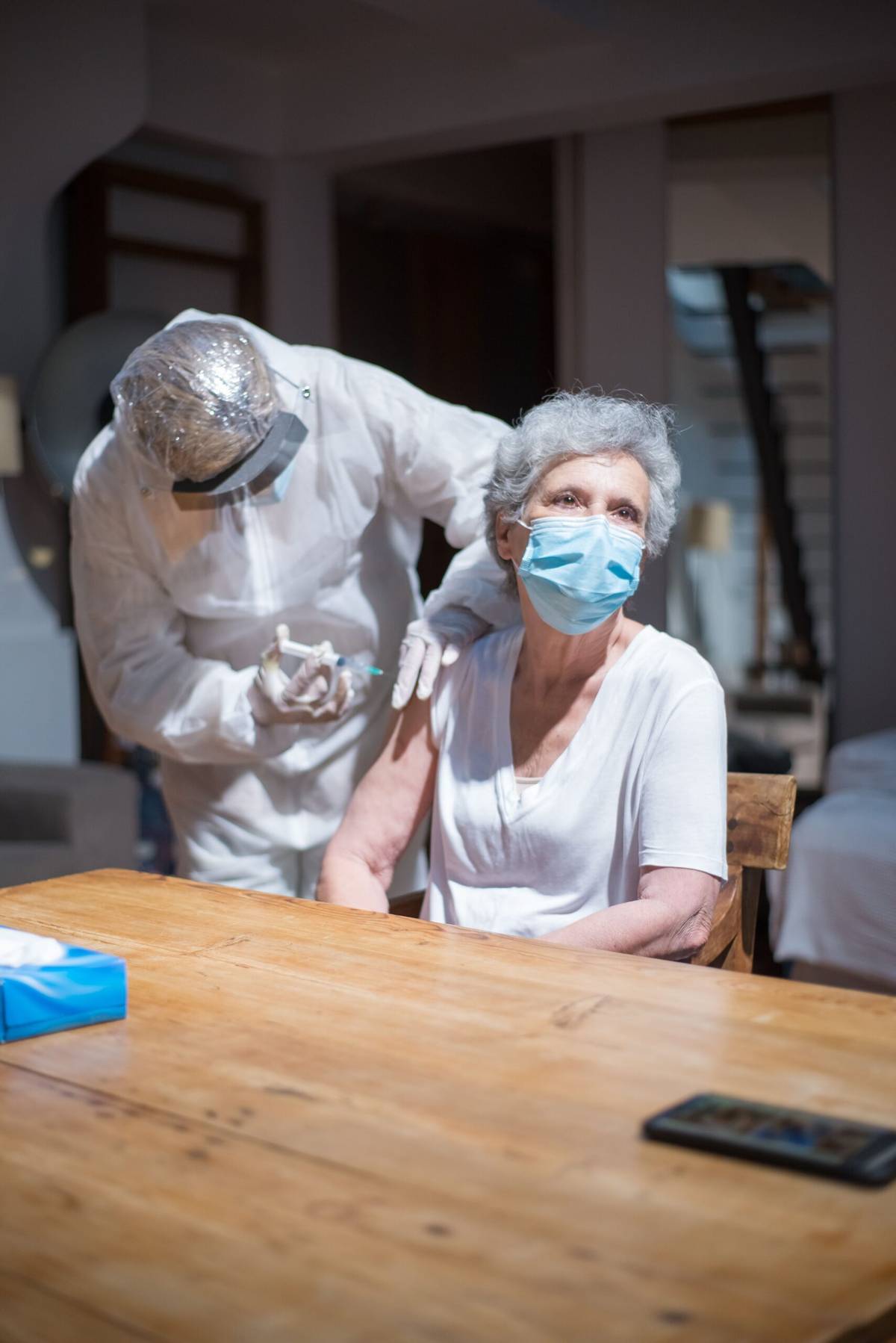 Healthcare professional giving a vaccine to an older woman