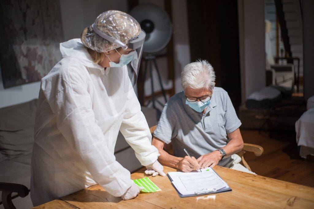 Older adult completing care assessment paperwork with support at home