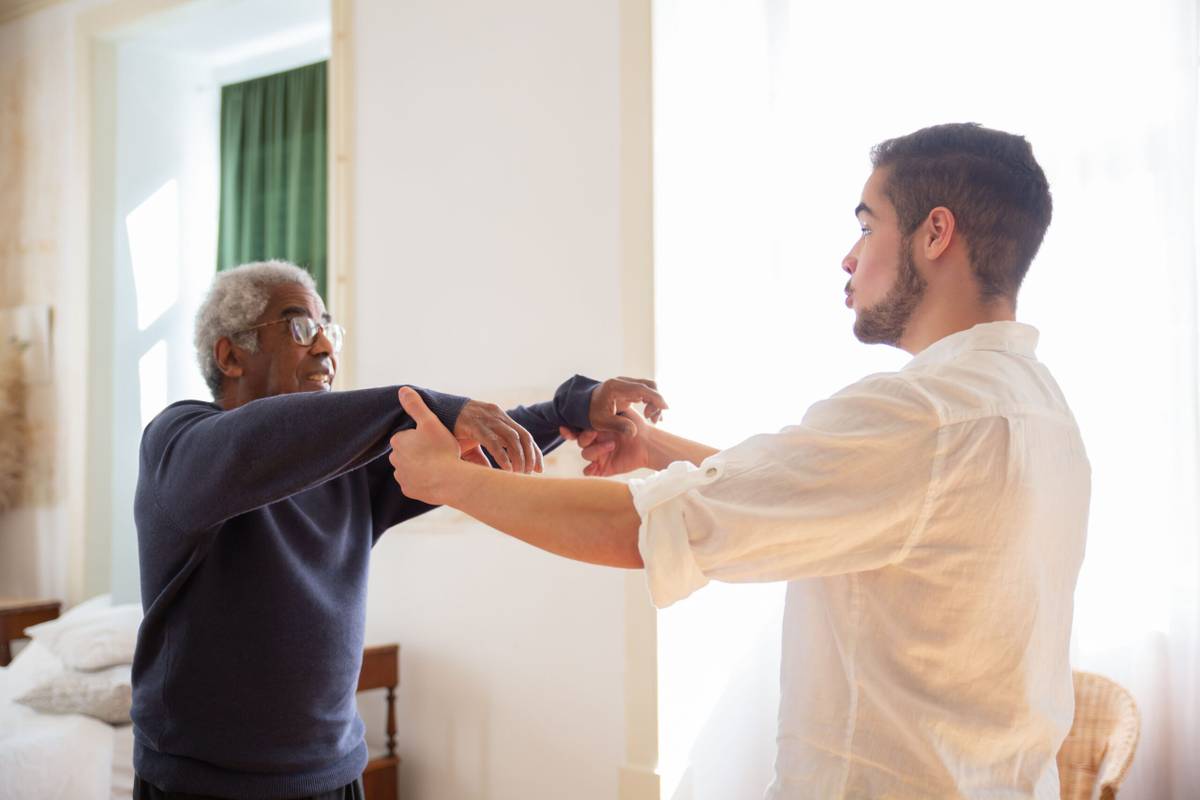 Older man talking with a younger adult who is supporting him at home