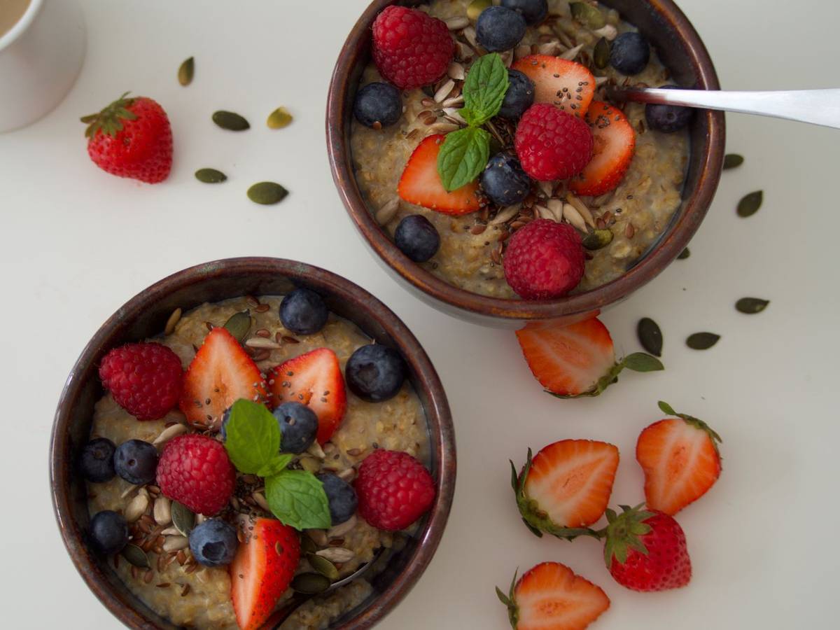 Bowl of oatmeal topped with fresh berries and seeds