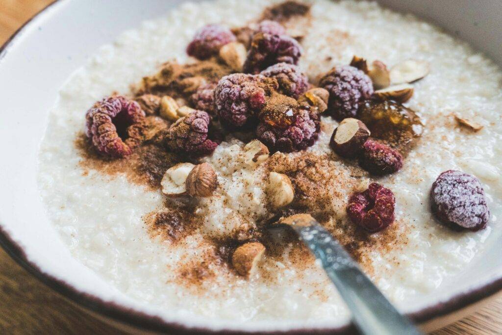 Bowl of oatmeal topped with raspberries and nuts for a high-fibre breakfast
