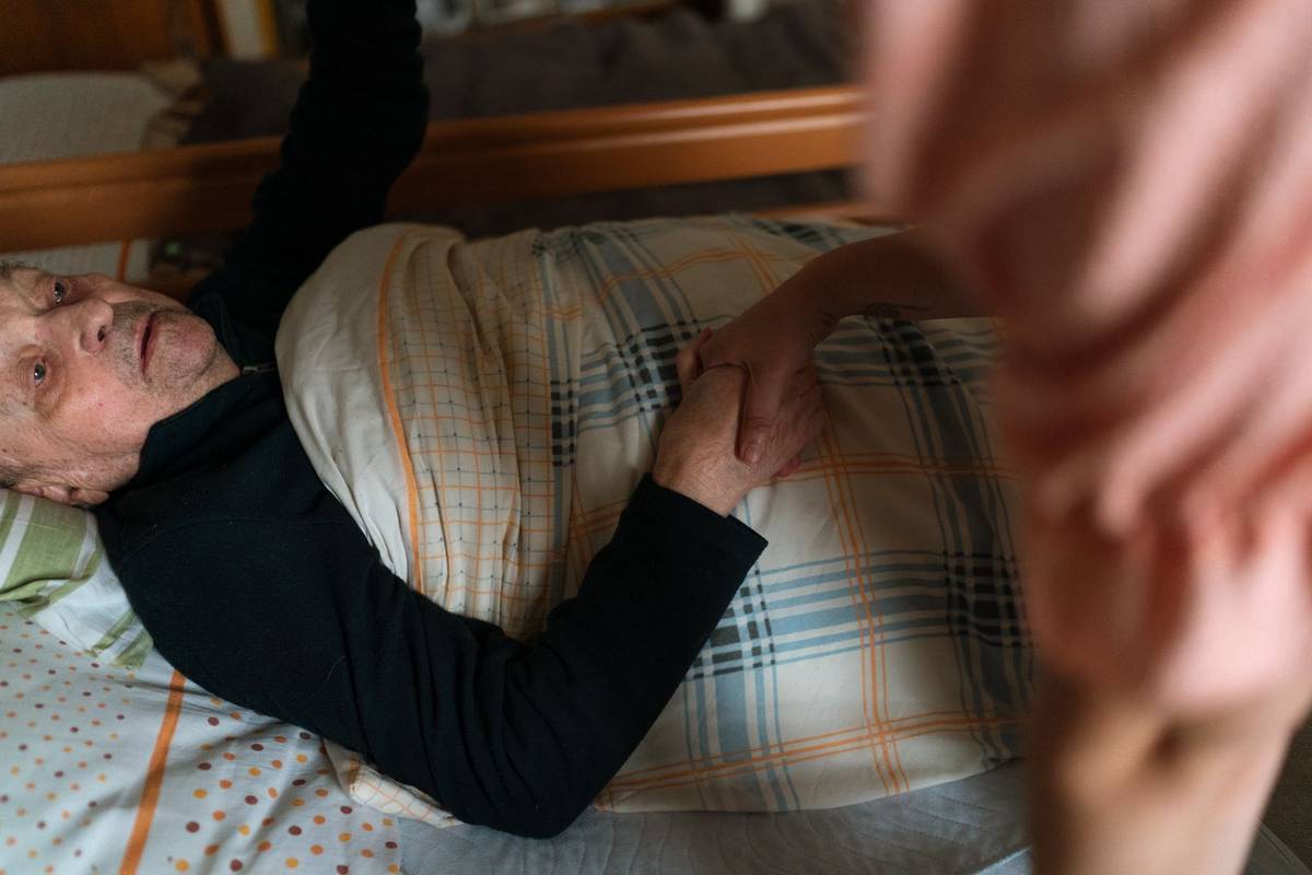 Caregiver holding hands with an older adult at home
