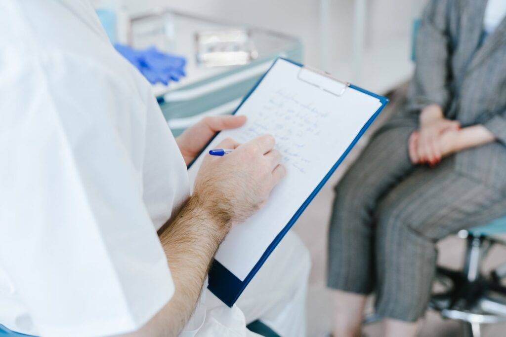 Doctor taking notes while discussing referral details with a patient