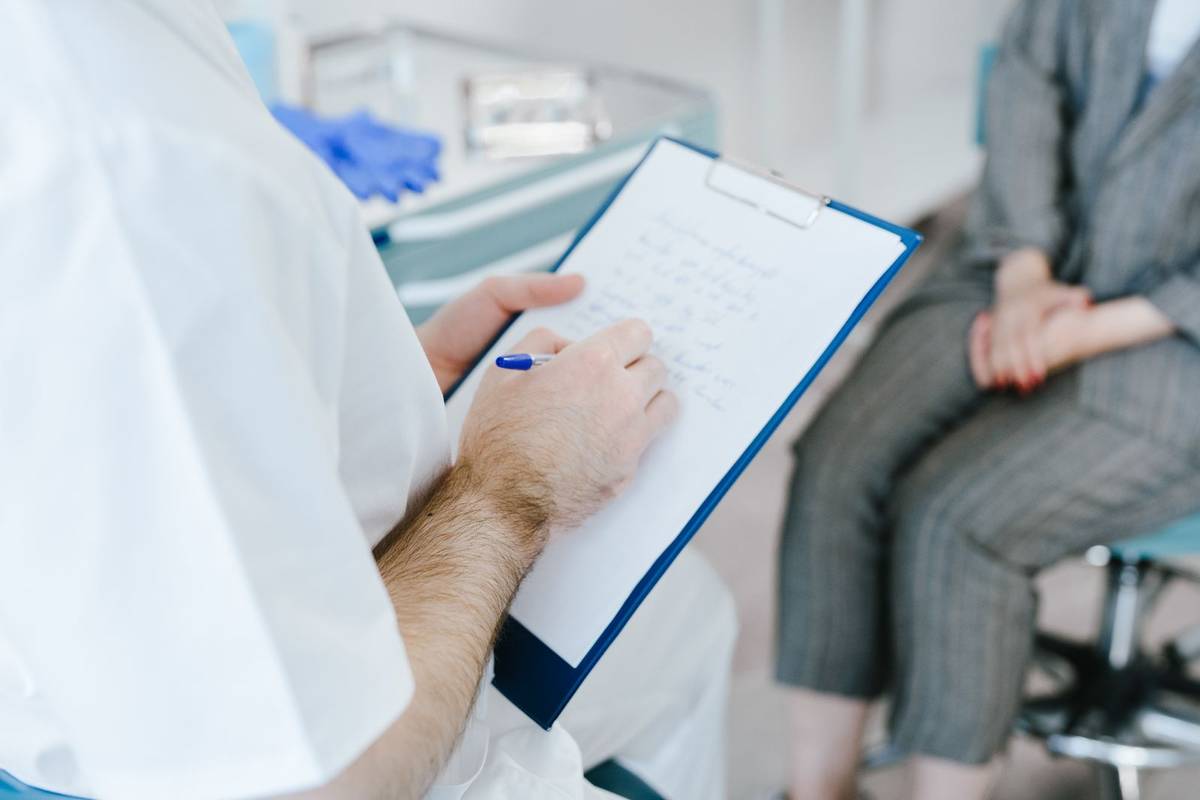 Doctor taking notes while discussing referral details with a patient