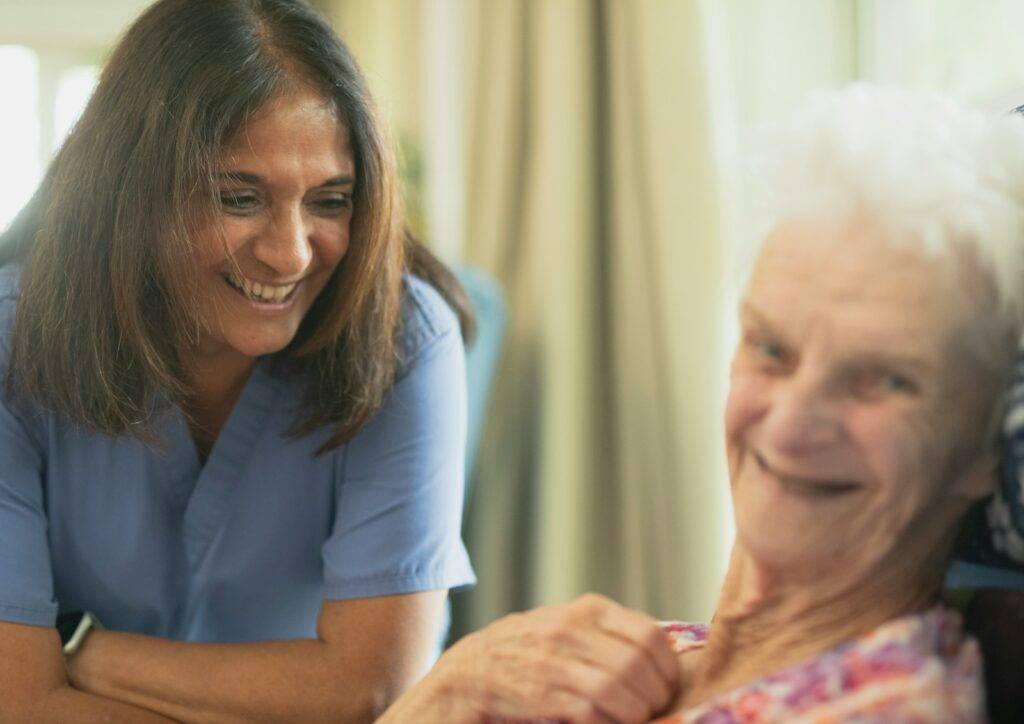Caregiver smiling with an older adult during supportive care