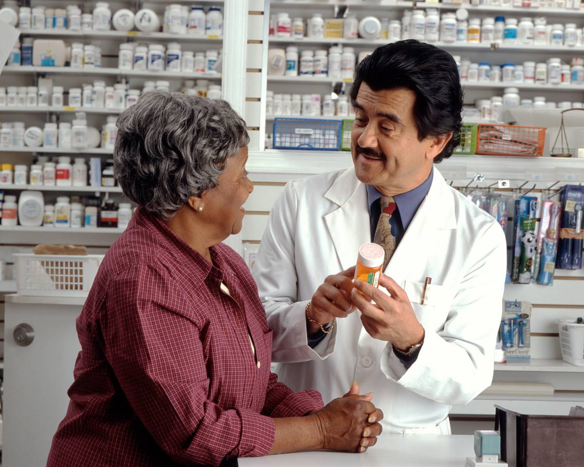 Pharmacist explaining prescription medicine to an older customer